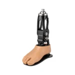 A black-and-silver mechanical prosthetic ankle supports a realistic flesh-toned artificial foot on a white background, conveying precision and mobility.